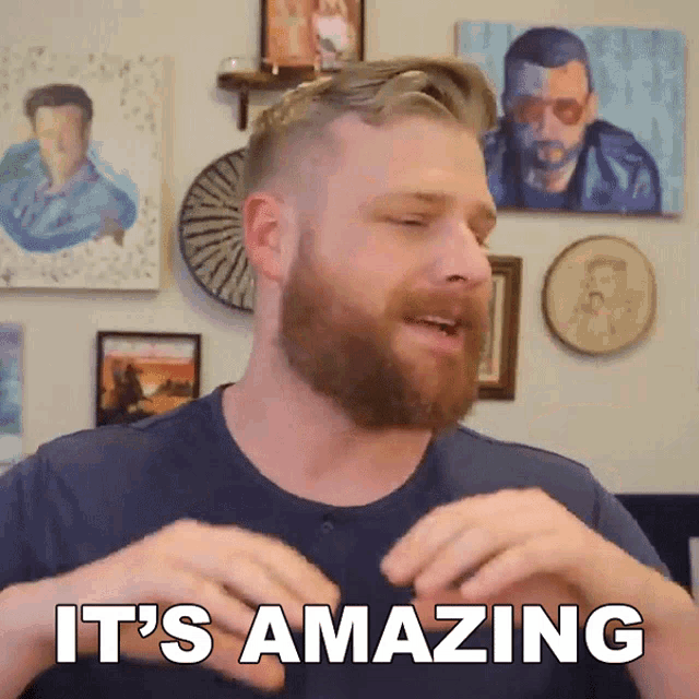 a man with a beard says it 's amazing in front of a wall of pictures