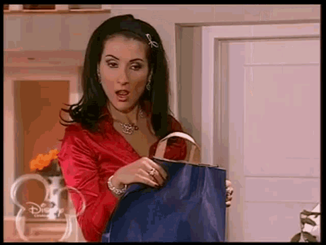 a woman in a red shirt is holding a blue bag ..