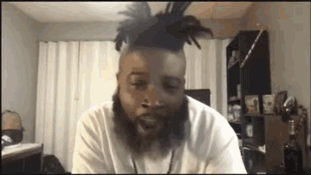 a man with dreadlocks and a beard is sitting in a room