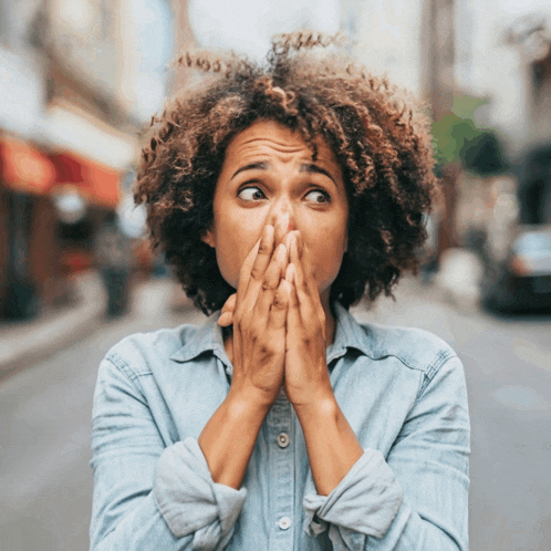 a woman is covering her mouth with her hands and making a funny face