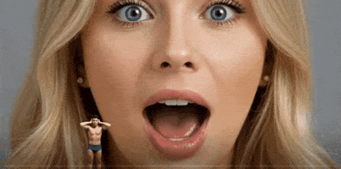 a close up of a woman 's face with her mouth open and a man standing next to her .