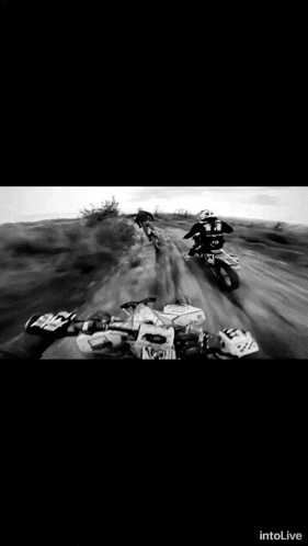 a black and white photo of a person riding a dirt bike with the word intolive on the bottom