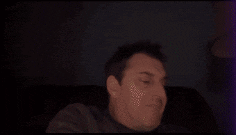 a man is sitting on a couch with his eyes closed and a purple light behind him .