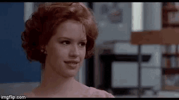 a woman with red hair is smiling in a room in a movie .