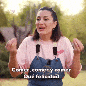 a woman in a pink shirt and blue apron says comer comer y comer qué felicidad