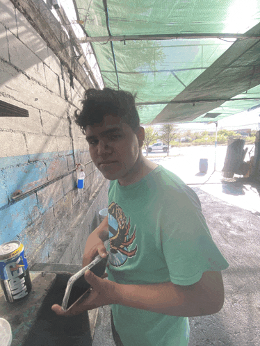 a young man wearing a green shirt with a frog on it