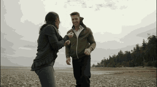a man and a woman are dancing on a beach