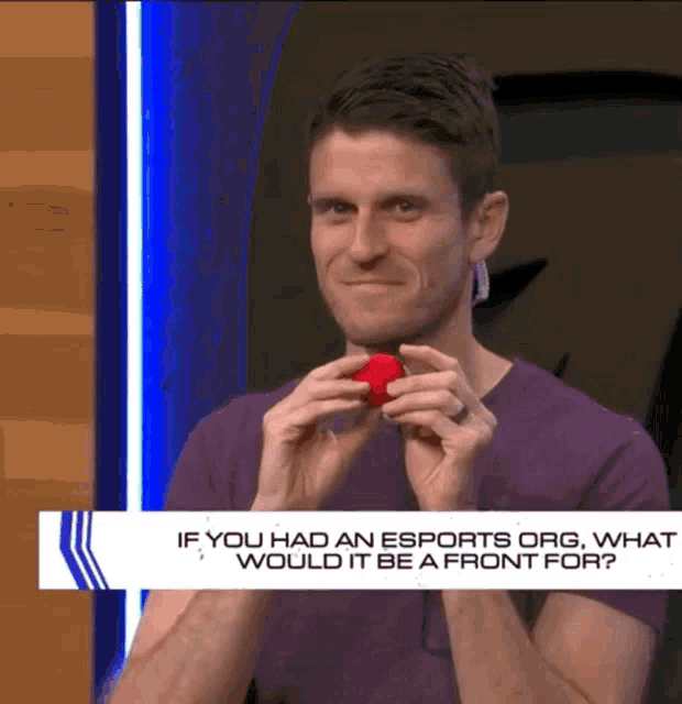 a man is holding a red ball in front of a sign that says if you had an esports org what would it be