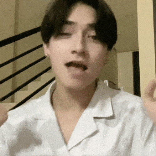 a young man in a white shirt is making a funny face with his mouth open