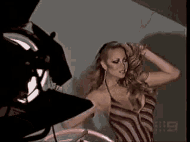 a woman in a striped dress is standing in front of a camera and a light .