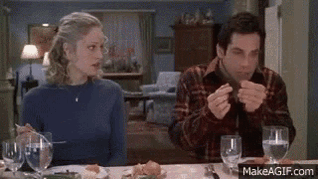 a man and a woman are sitting at a table eating a meal .
