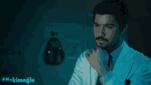 a man in a lab coat has the hashtag #hekimoglu on the bottom right