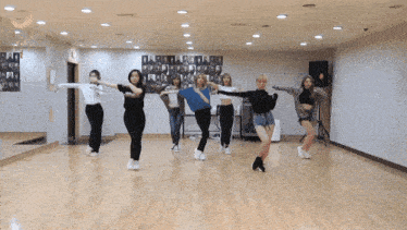 a group of women are dancing in a room with a mirror