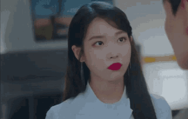 a woman with red lipstick is looking at a man in a room .