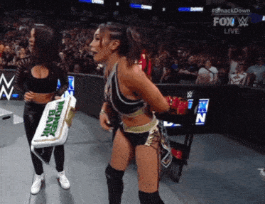 a female wrestler holds a sign that says money in the bank