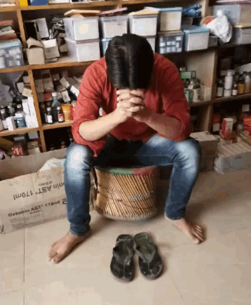 a man sits on a stool in front of a box that says 170ml on it