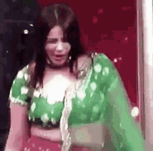 a woman in a green crop top and red skirt is dancing .