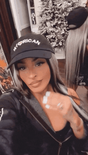 a woman wearing a hat with the word rican on it is taking a selfie .
