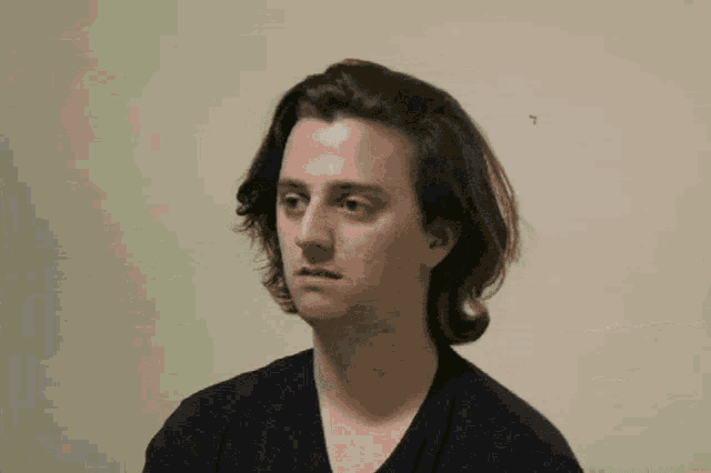 a young man with long hair is wearing a black shirt
