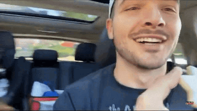 a man in a car wearing a t-shirt that says " the a " on it