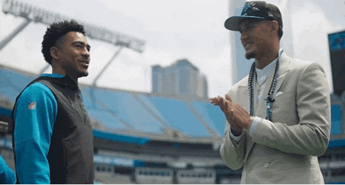 two men are standing next to each other in a stadium and one is wearing a nfl jersey