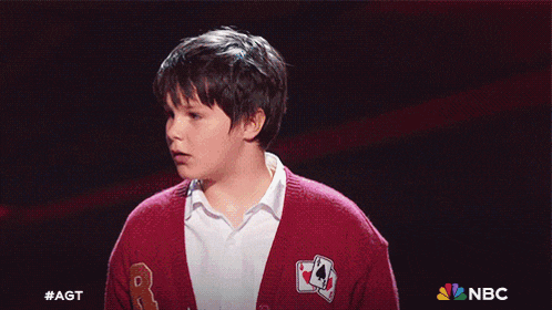 a young boy wearing a red sweater with a playing card on it