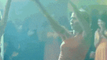 a woman in a red dress is dancing with her arms in the air
