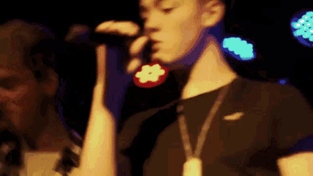 a man is singing into a microphone while another man looks on .