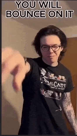 a man in a black shirt and glasses is pointing at the camera .