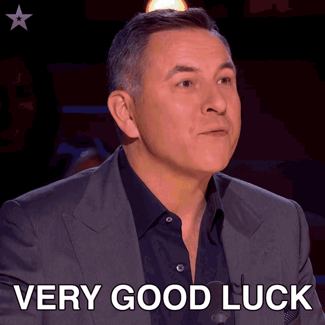 a man in a suit says " very good luck " on a screen
