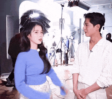 a woman in a blue sweater stands next to a man in a white jacket