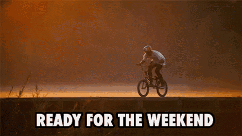 a man is riding a bike in the air with the words `` ready for the weekend '' behind him .
