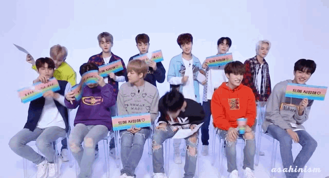 a group of young men are sitting in chairs and holding signs that say ' human made '