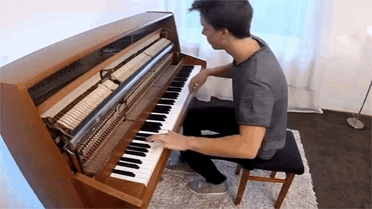 a young man is playing a piano in a room