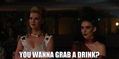 two women are standing next to each other and the words `` you wanna grab a drink ? '' are on the screen .