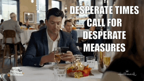 a man is sitting at a table with a glass of wine looking at his phone with the words desperate times call for desperate measures