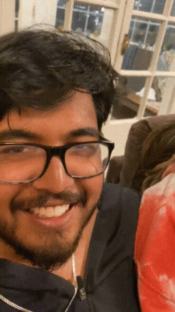 a man wearing glasses and a beard smiles for the camera