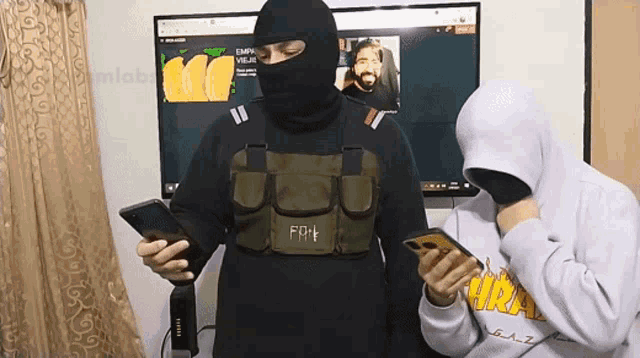 a man wearing a mask is looking at his phone while another man looks on