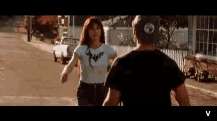 a man and a woman are standing next to each other on the side of a street .