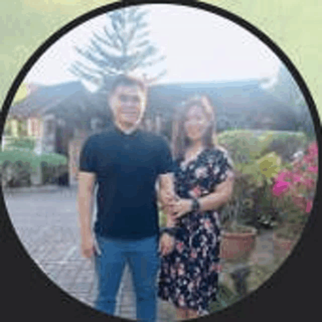 a man and a woman are standing next to each other in a circle in front of a house .