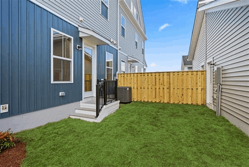 the backyard of a house with a wooden fence and a lawn