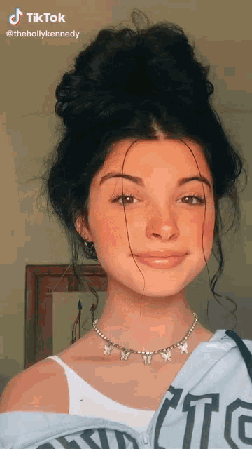 a girl wearing a butterfly necklace and a shirt that says ' tc ' on it