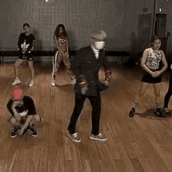 a group of people are dancing in a room with a wooden floor .