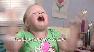 a little girl is sitting on a couch with her mouth open and screaming .