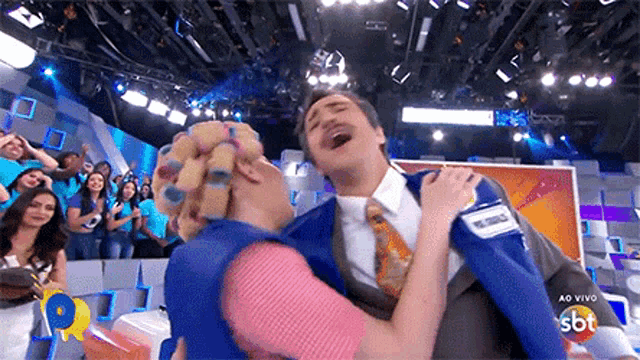 a man in a suit and tie is being held by a woman in a blue vest with a sbt logo in the corner