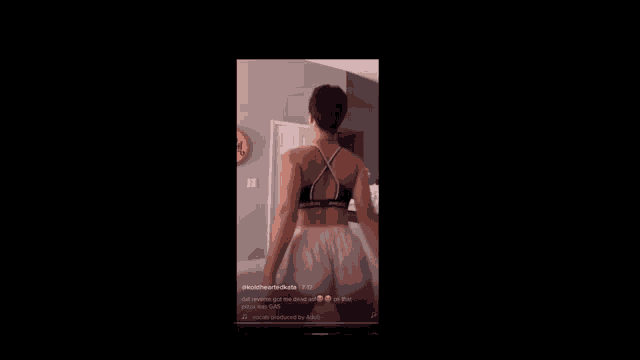 a woman in a black bra and white shorts is dancing on a black screen .