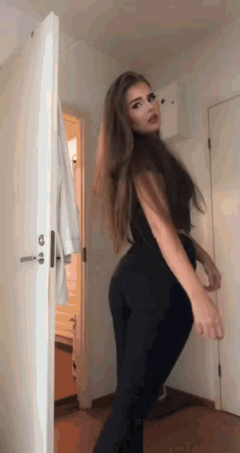 a woman with long hair is standing in front of a white door .