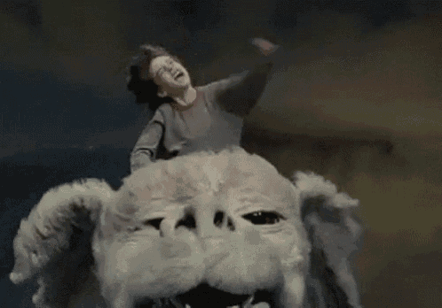 a boy is riding on the back of a white monster .