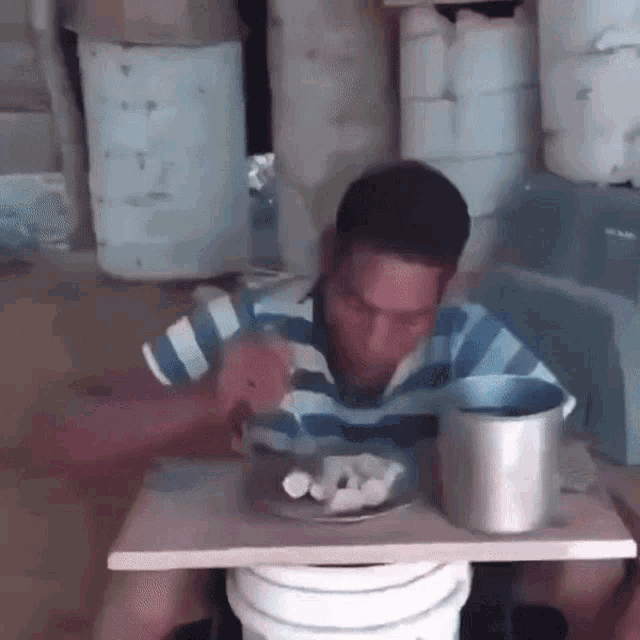a man in a striped shirt sits at a table with a plate of food