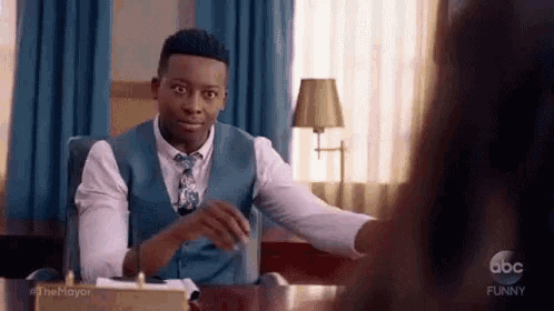 a man in a suit and tie is sitting at a desk in front of a woman .